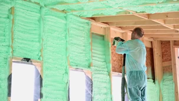 Male Builder Insulating Wooden Frame House Man Worker Spraying Polyurethane — Wideo stockowe