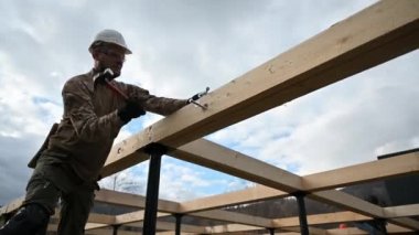 Yığınla temele ahşap çerçeve inşa eden bir işçi. Marangoz çekiçle tahta kirişe çekiç çakıyor, çekiç kullanıyor. Marangozluk kavramı.