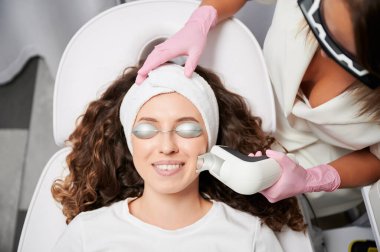 Close-up view laser correction process of vascular asterisks on face in clinic of hardware cosmetology. Doctor working with modern yellow laser for treating vascular defects of face and body.