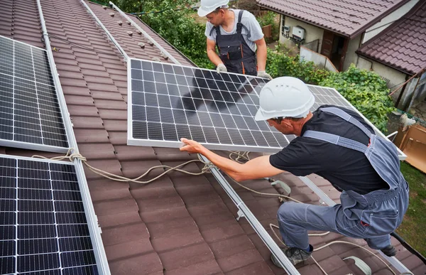 Men Technicians Carrying Photovoltaic Solar Moduls Roof House Engineers Helmets — Stockfoto