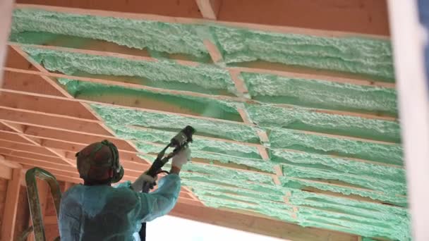 Male Builder Insulating Wooden Frame House Man Worker Spraying Polyurethane — Vídeo de Stock