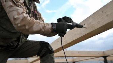 Ahşap çerçeve inşa eden adam. Gelecekteki kulübelerin ahşap çerçevesinde elektrikli matkapla delik açan işçiler. Marangozluk kavramı.