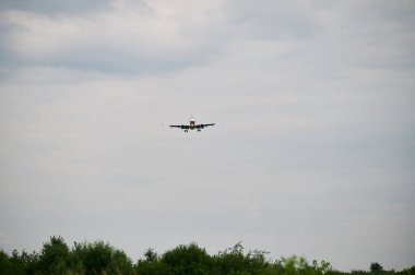 Gökyüzünde uçan ticari uçak. Bulutlu bir havada uçağın inişi ön planda. Seyahat kavramı.