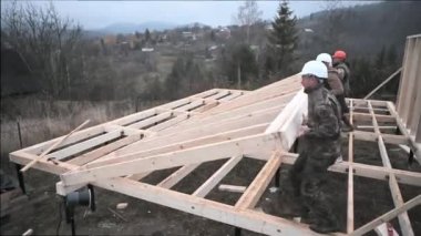 Erkek işçiler temel üzerine ahşap çerçeve inşa ediyorlar. Bir grup inşaatçı gelecekteki ev için ahşap çerçeve dikiyorlar. İnşaat konsepti