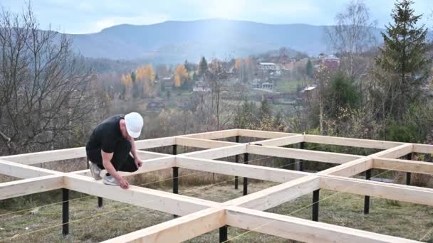 工人在桩基础上建造木制框架房屋 木匠测量木板 并用铅笔做记号 木匠概念 — 图库视频影像