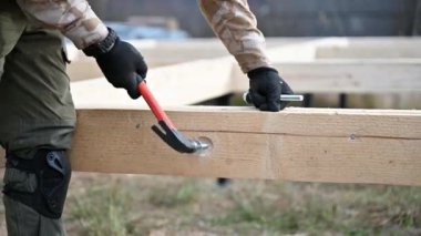 Yığınla temele ahşap çerçeve inşa eden bir işçi. Marangoz çekiçle tahta kirişe çekiç çakıyor, çekiç kullanıyor. Marangozluk kavramı.