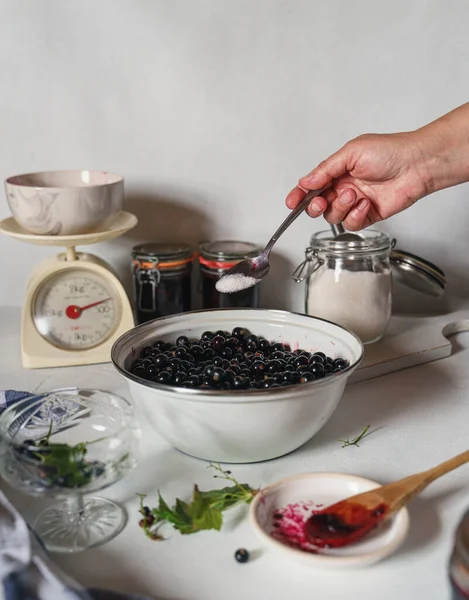 Ženy ruce přidání cukru do ostružin při výrobě marmelády — Stock fotografie
