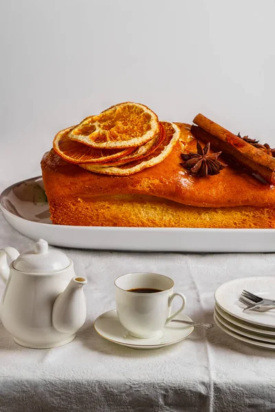 Гигантский апельсиновый и коричный кекс на тарелке на столе с крошечной посудой — стоковое фото