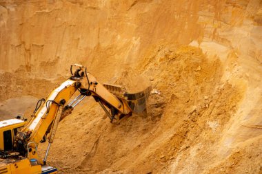 Büyük sarı hidrolik endüstriyel kazıcı, demir kovası madencileri, büyük kumlu bir kariyerin içinde kum kazma ve yükleme,. 