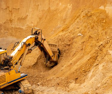 Büyük sarı hidrolik endüstriyel kazıcı, demir kovası madencileri, büyük kumlu bir kariyerin içinde kum kazma ve yükleme,. 