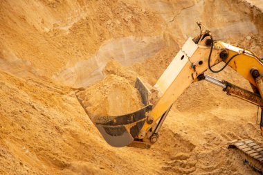 Büyük sarı hidrolik endüstriyel kazıcı, demir kovası madencileri, büyük kumlu bir kariyerin içinde kum kazma ve yükleme,. 