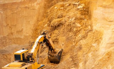 Büyük sarı hidrolik endüstriyel kazıcı, demir kovası madencileri, büyük kumlu bir kariyerin içinde kum kazma ve yükleme,. 