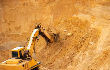 Büyük sarı hidrolik endüstriyel kazıcı, demir kovası madencileri, büyük kumlu bir kariyerin içinde kum kazma ve yükleme,. 