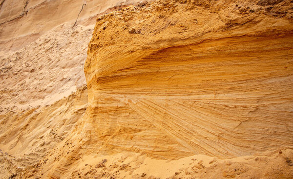 Текстурный песок с рельефной поверхностью, разноцветные слои и разного размера гранул, в карьере наружного песка, после добычи руды и песка для строительства. 