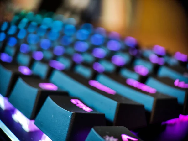 Gamer keyboard with neon backlight macro defocused close up. Online games and virtual reality concept background.