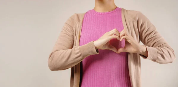 捐赠和慈善概念 年轻义工女性制作心形吊饰 的特写 用粉色和身体语言表示乳腺癌意识的标志 — 图库照片