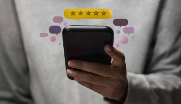 Customer Experiences Concept. Happy Client Using Smartphone to Submit Five Star Review Rating for Online Satisfaction Surveys. Positive Feedback on Mobile Phone