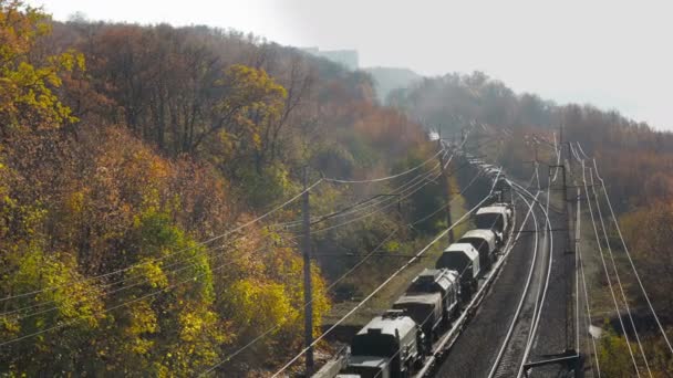 用铁路 车辆和武器运输军事装备 沿着被五彩斑斓的森林覆盖的山脉的铁路 俄文本 — 图库视频影像