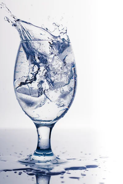Spruzzare dal cubetto di ghiaccio in un bicchiere d'acqua, isolato sullo sfondo bianco — Foto Stock