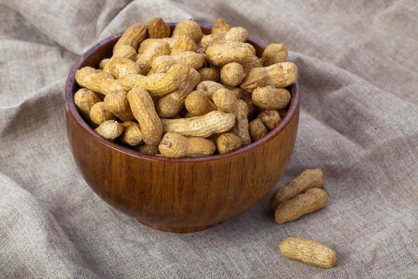 Peanuts in a wooden bowl on the background fabric — Stock Photo, Image