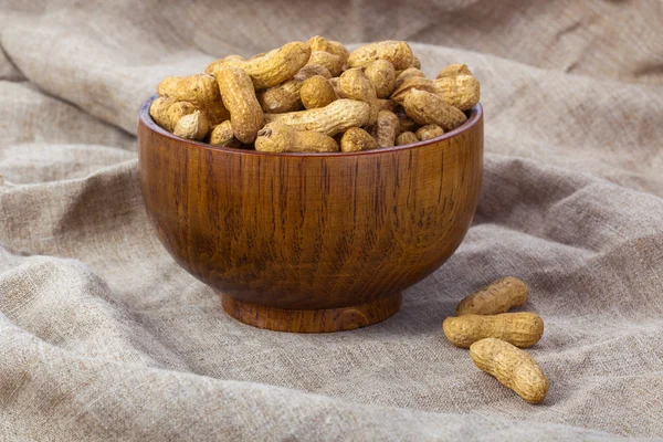 Peanuts in a wooden bowl on the background fabric — Stock Photo, Image