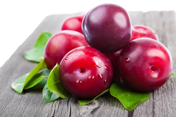 Fresh plums with green leaves — Stockfoto