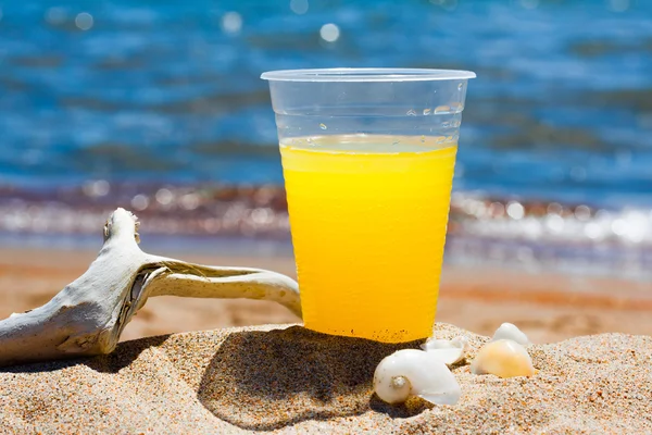 Пластиковый стакан с коктейлем на берегу моря — стоковое фото