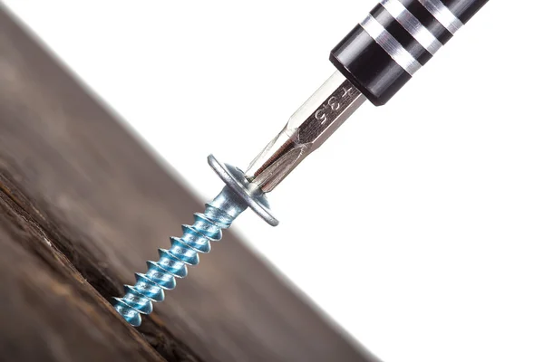 Eine Schraube, die mit einem Schraubenzieher in Holz eingeschraubt wird — Stockfoto