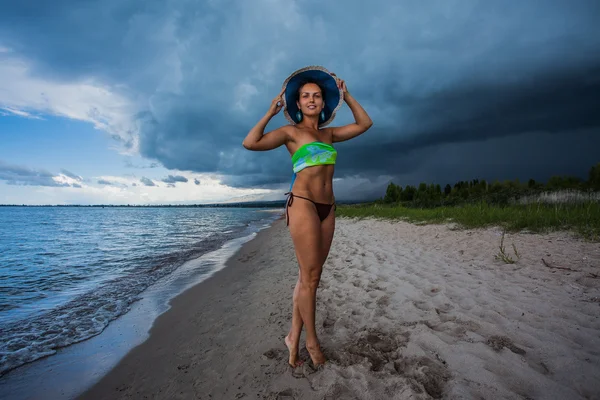 Sexy Dame mit Hut am stürmischen Strand — Stockfoto