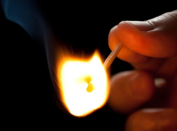 Hand holding a burning match — Stock Photo, Image