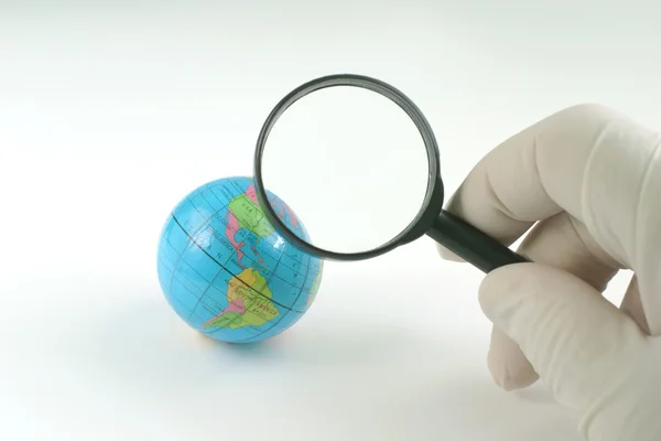 Earth globe & magnifying glass — Stock Photo, Image