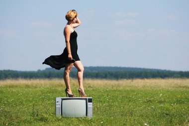 alanların ortasında eski bir tv ile kız