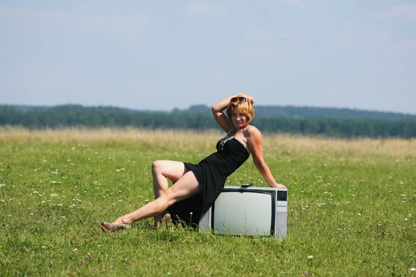 Meisje met oude tv in het midden van de velden — Stockfoto
