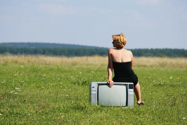 Meisje met oude tv in het midden van de velden — Stockfoto