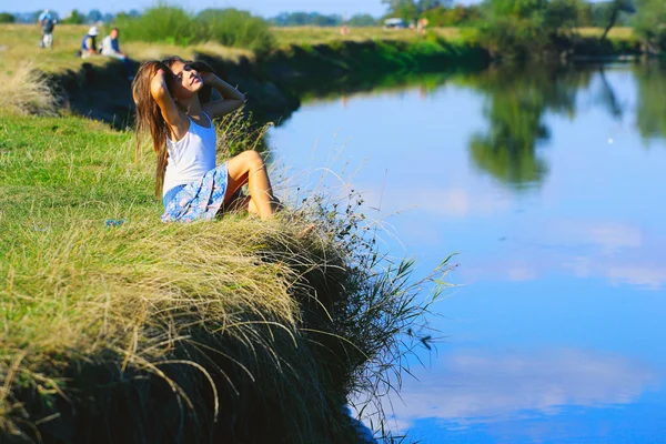 小女孩坐在河海岸线在夏日时光 免版税图库图片