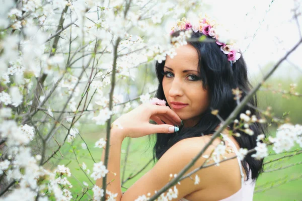 Chica agradable relajado cerca de ramas de flores —  Fotos de Stock