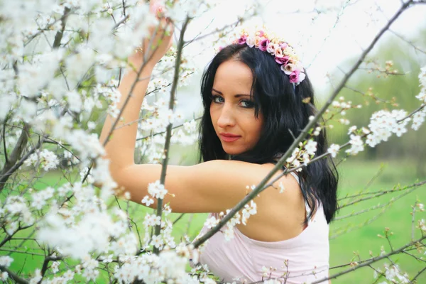 Chica agradable relajado cerca de ramas de flores — Foto de Stock