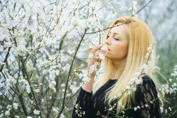 Chica agradable relajado cerca de ramas de flores — Foto de Stock