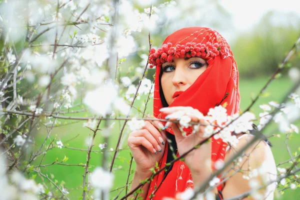 Chica agradable relajado cerca de ramas de flores — Foto de Stock