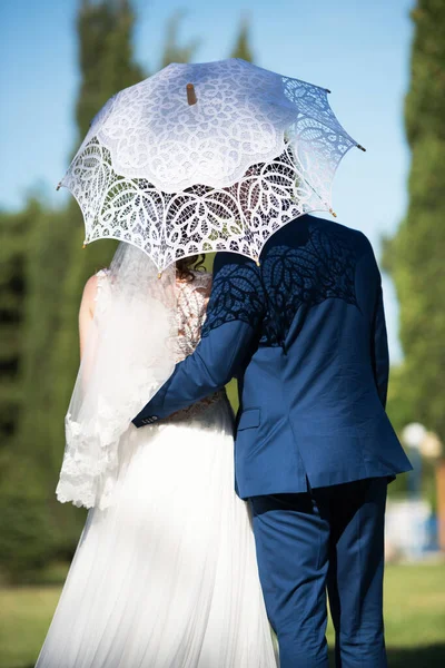 結婚式の日にレースの傘の下で抱擁花嫁と新郎 選択的な焦点 — ストック写真
