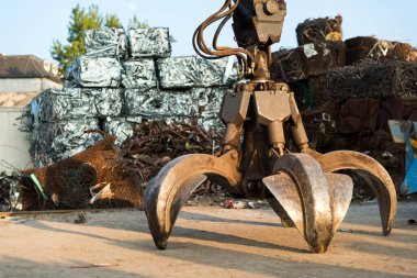 Large tracked excavator working a steel pile at a metal recycle yard. Industrial scrap metal recycling - selective focus, copy space clipart