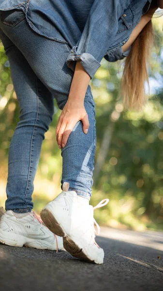 leg pain, cramp after cycling girl in jeans. High quality photo