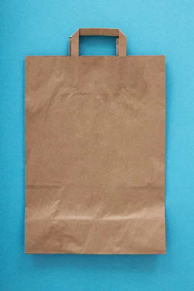 Folded paper bag with a handle on a Blue background. Layout for advertising High quality photo