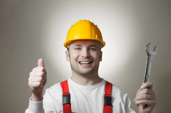 Sonriente joven trabajador con una llave inglesa — Foto de Stock