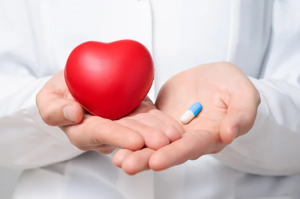 Doctor holding a heart and a pill — Stock Photo, Image