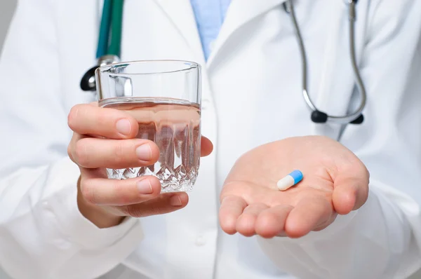 Dottore in possesso di un bicchiere d'acqua e una pillola — Foto Stock