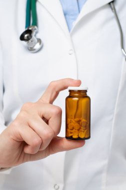 Doktor elinde bir şişe ilaç tutuyor.
