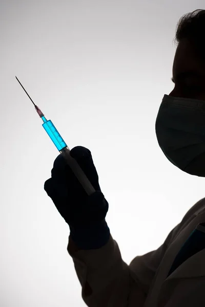 Silhouette of a doctor with syringe filled with blue liquid. Vaccination concept. — Stock Photo, Image