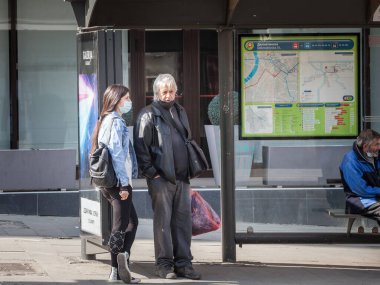 BELGRAD, SERBIA - 28 Mart 2021: Genç ve yaşlı kadınlar, Coronavirus covid 19 krizi sırasında Belgrad otobüs durağında ulaşımı bekleyen bir solunum maskesi takıyorlar