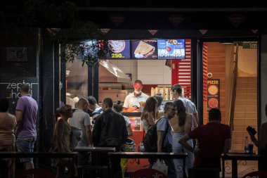 BELGRAD, SERBIA - 11 AĞUSTOS 2021: Bir pizza fast food restoranında çalışan personelin Coronavirus Covid 19 krizinde yüz maskesi takarak sosyal mesafelere saygı duymayan insanlarla ilgilenmesi